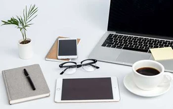 Illustration of consumer electronic devices — laptop, tablet and phones — on a desk